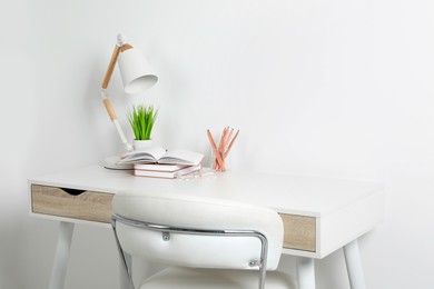 Comfortable workplace with white desk near wall. Space for text