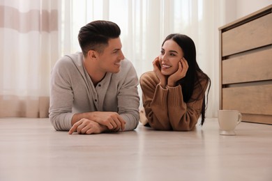 Photo of Happy couple lying on warm floor at home. Heating system