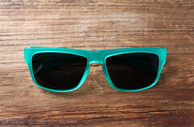 Photo of Stylish sunglasses on wooden background, top view