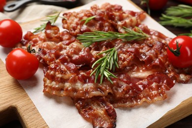 Photo of Slices of tasty fried bacon, rosemary and tomatoes on table, closeup