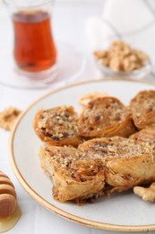 Photo of Eastern sweets. Pieces of tasty baklava on white tiled table, closeup