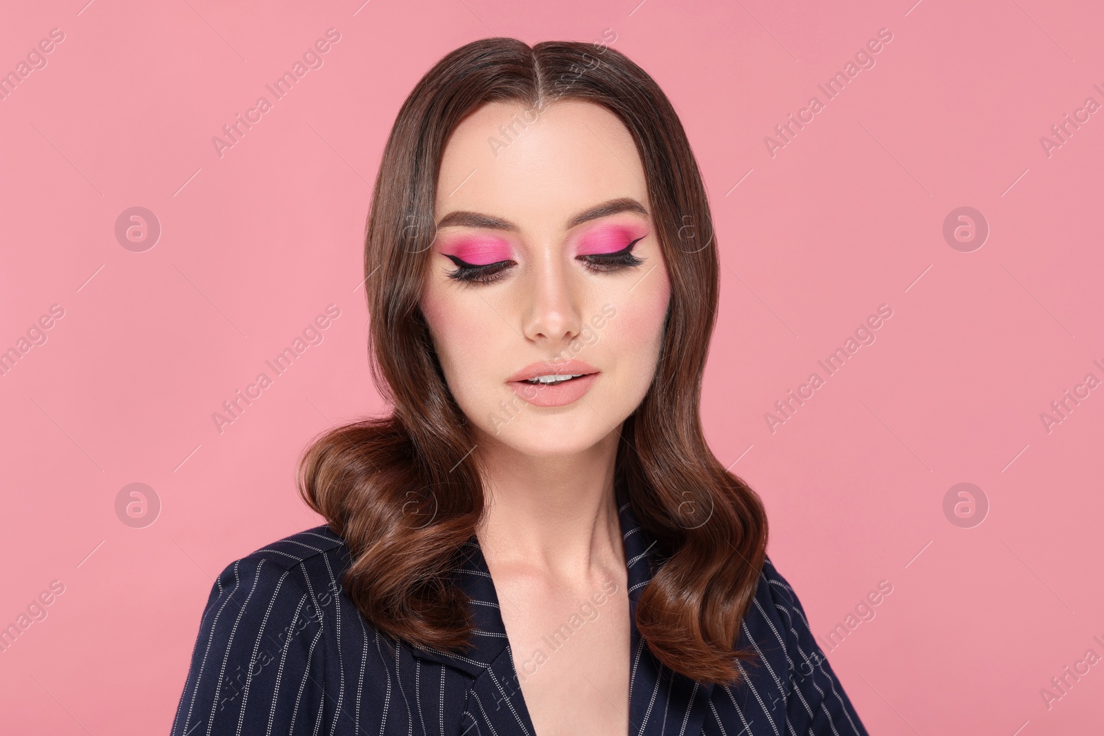 Photo of Portrait of beautiful young woman with makeup and gorgeous hair styling on pink background