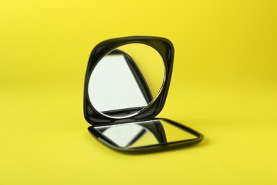 Stylish cosmetic pocket mirror on yellow background