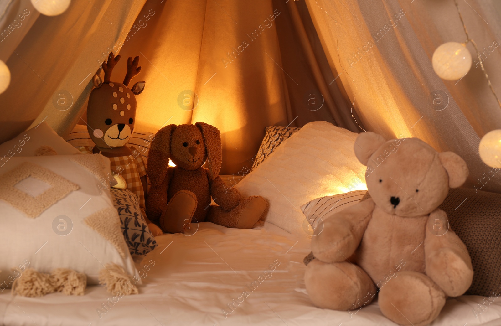 Photo of Play tent with toys and pillows indoors, closeup. Modern children's room interior