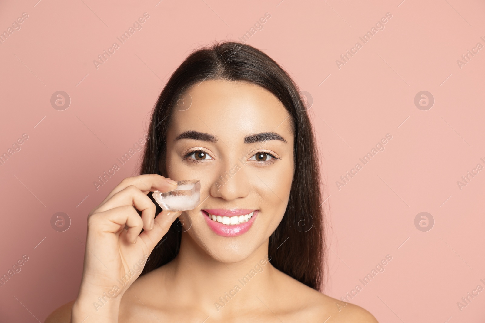 Photo of Young woman with ice cube on color background. Skin care