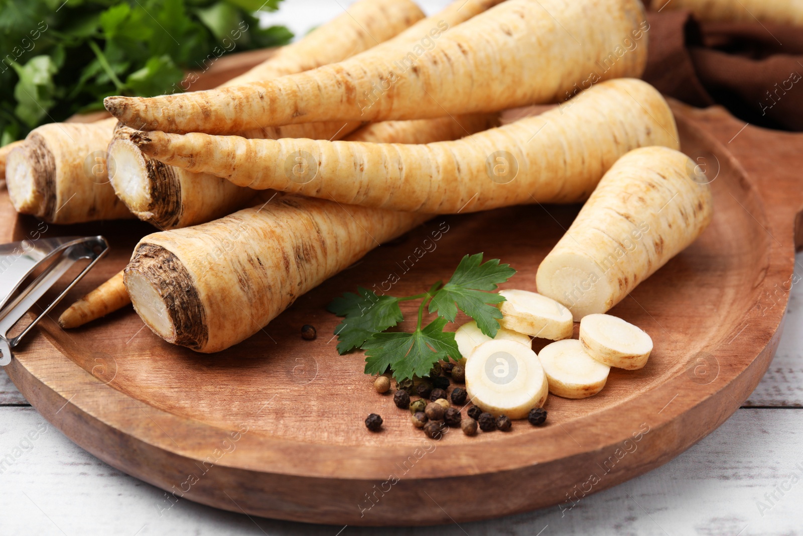 Photo of Raw parsley roots and fresh herb on wooden board, closeup