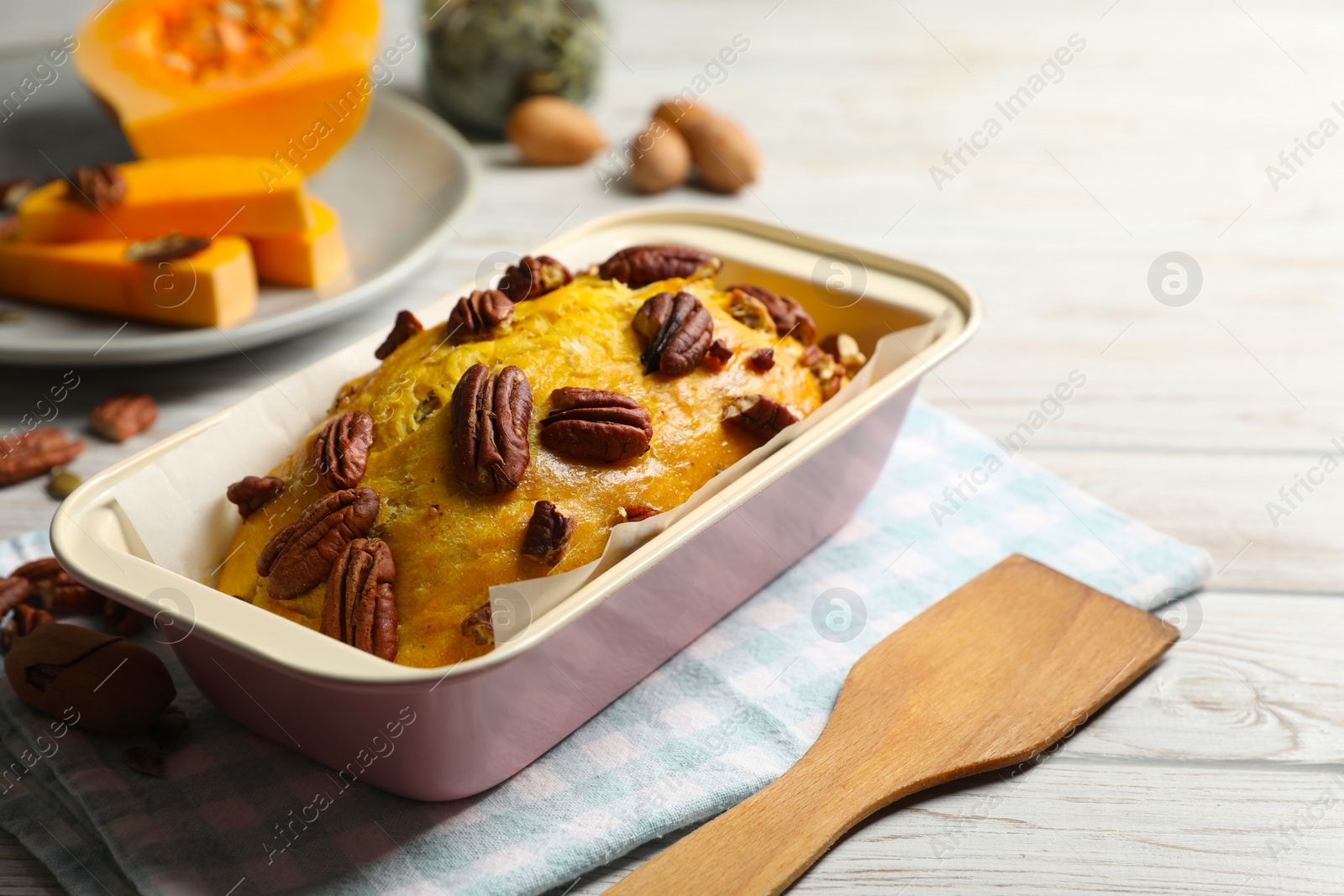 Photo of Delicious pumpkin bread with pecan nuts on light wooden table. Space for text