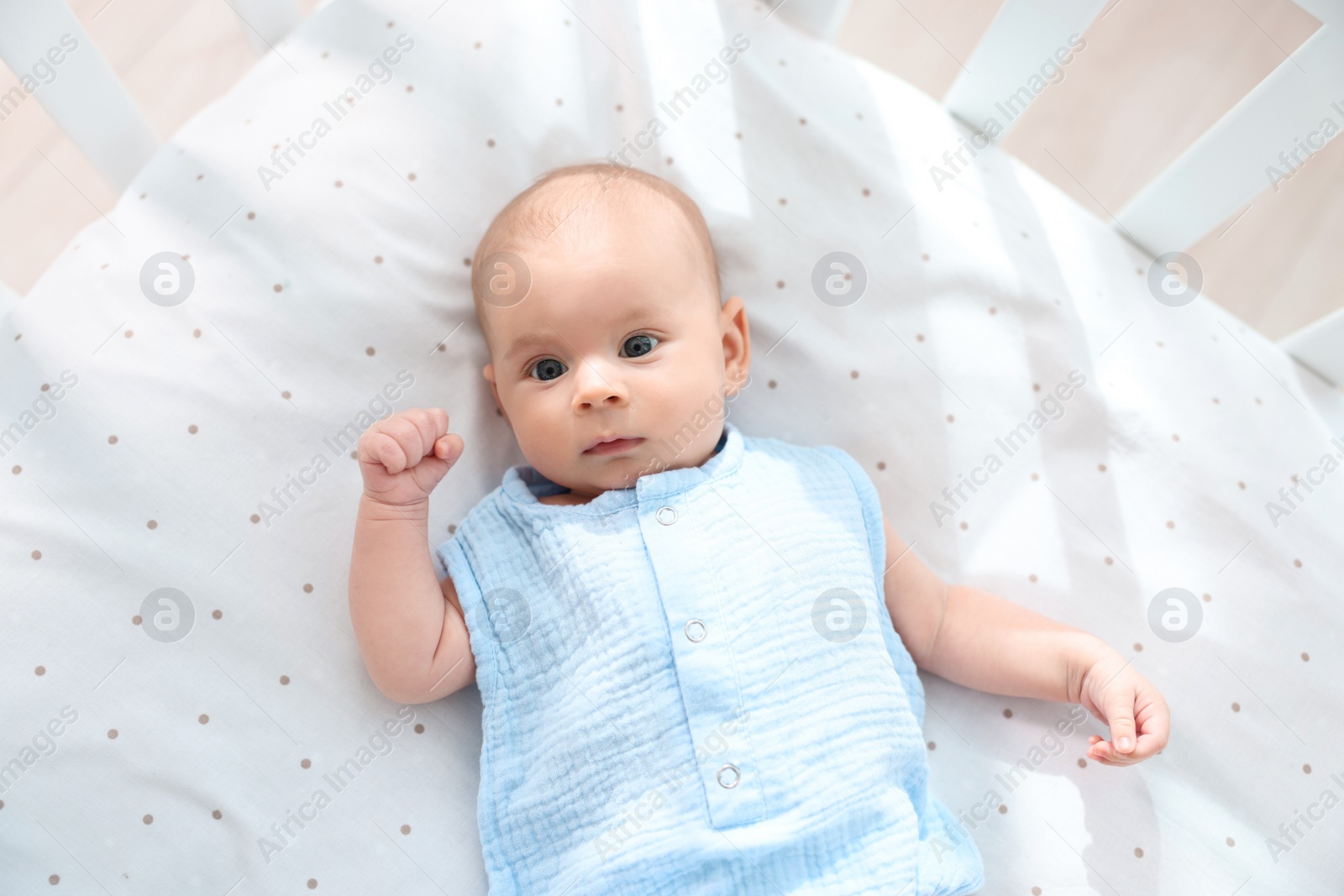 Photo of Cute little baby lying in crib at home, top view