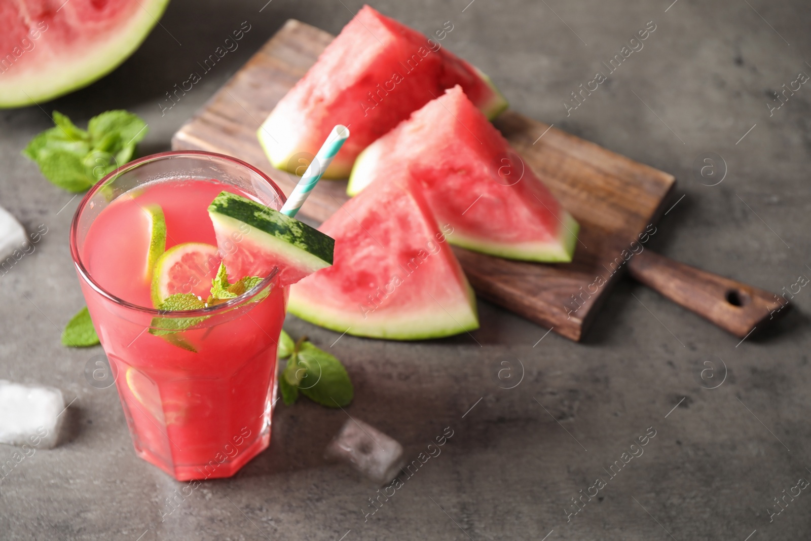 Photo of Glass of tasty refreshing drink with watermelon on grey table