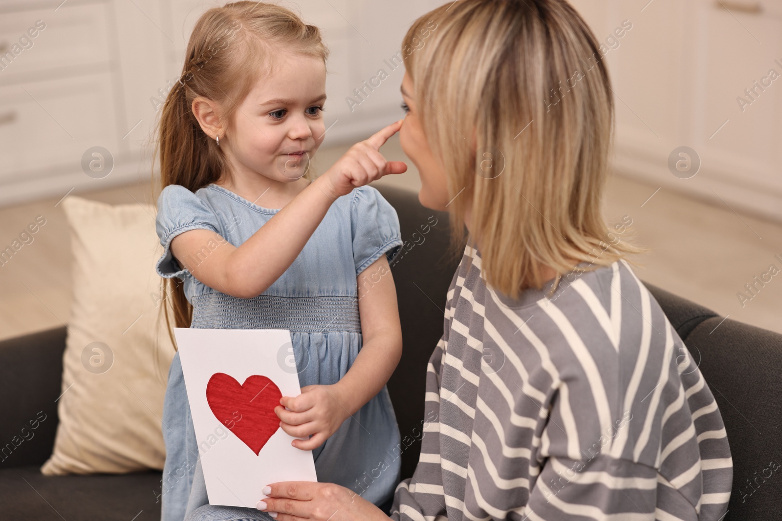 Photo of Little daughter congratulating her mom with greeting card at home. Happy Mother's Day