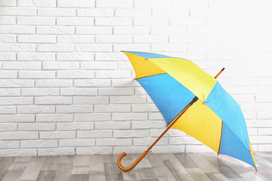 Beautiful colorful umbrella near white brick wall. Space for text