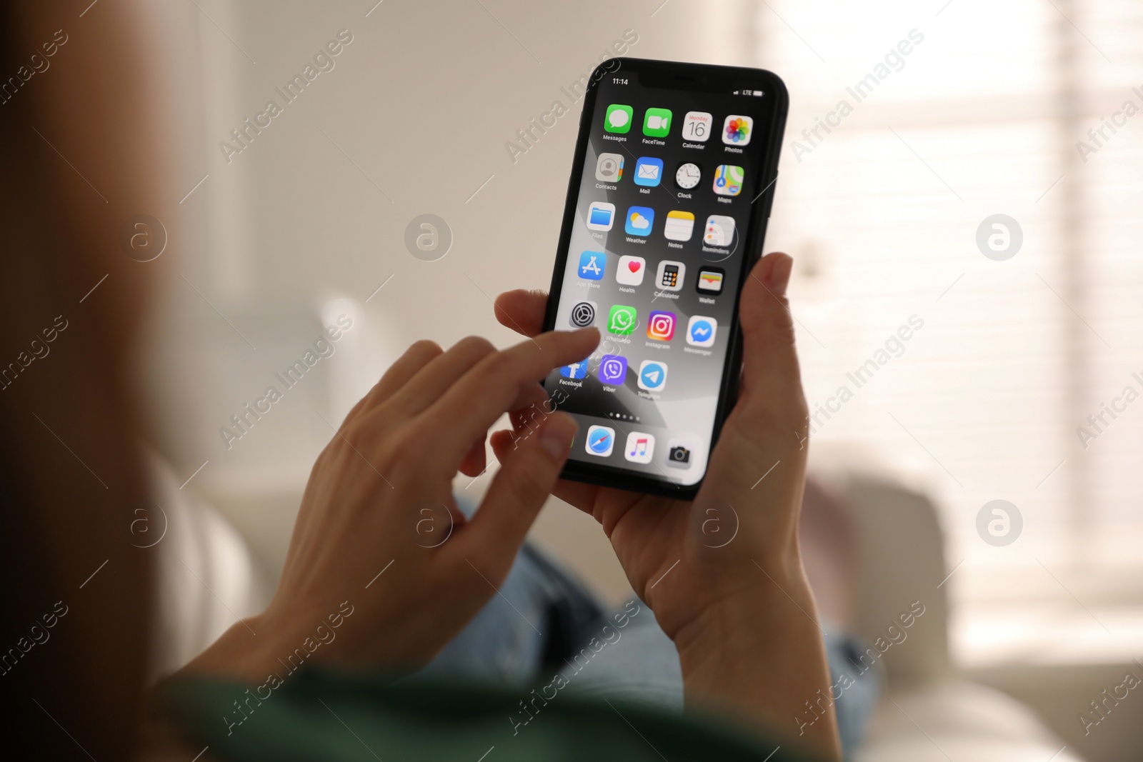 Photo of MYKOLAIV, UKRAINE - MARCH 16, 2020: Woman holding iPhone 11 with home screen indoors, closeup