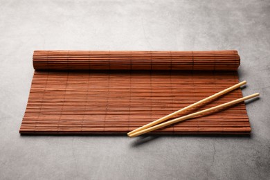 Rolled bamboo mat and chopsticks on grey table