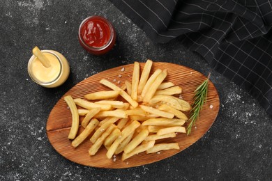Photo of Delicious french fries served with sauces on grey textured table, flat lay