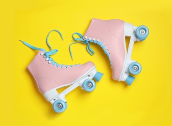 Pair of stylish quad roller skates on color background, top view