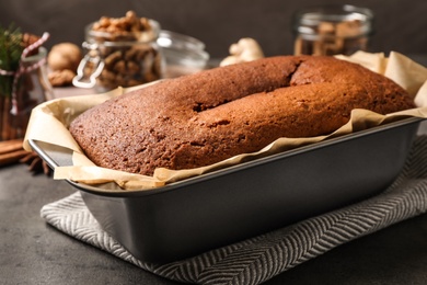 Delicious gingerbread cake in baking dish on grey table, closeup
