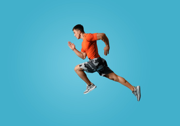 Athletic young man running on light blue background, side view