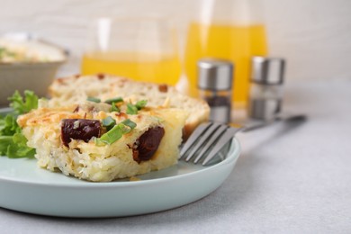 Photo of Tasty sausage casserole with green onion served on light grey table, closeup