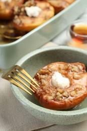 Tasty baked quince with nuts and cream cheese in bowl on table, closeup