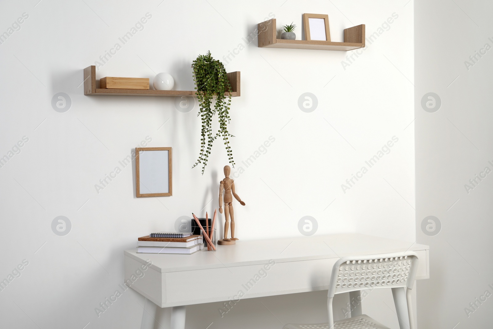 Photo of Comfortable workplace with white desk near wall at home