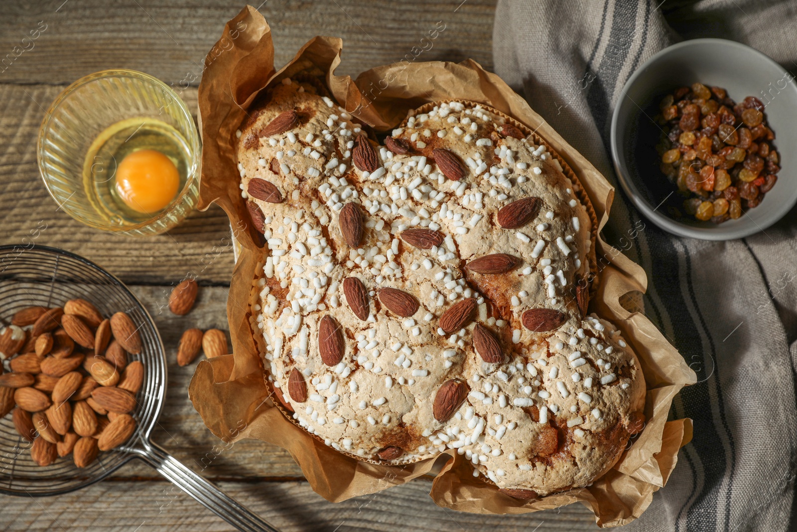 Photo of Delicious Italian Easter dove cake (traditional Colomba di Pasqua) and ingredients on wooden table, flat lay