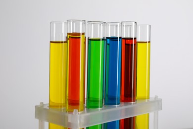 Photo of Test tubes with liquids in stand on white background, closeup