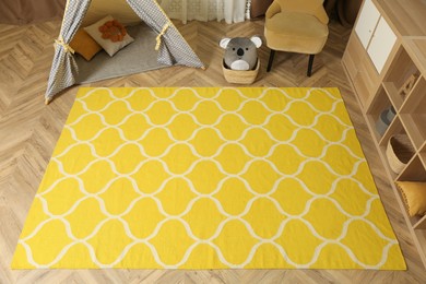 Modern children's room interior with yellow carpet and stylish furniture, above view