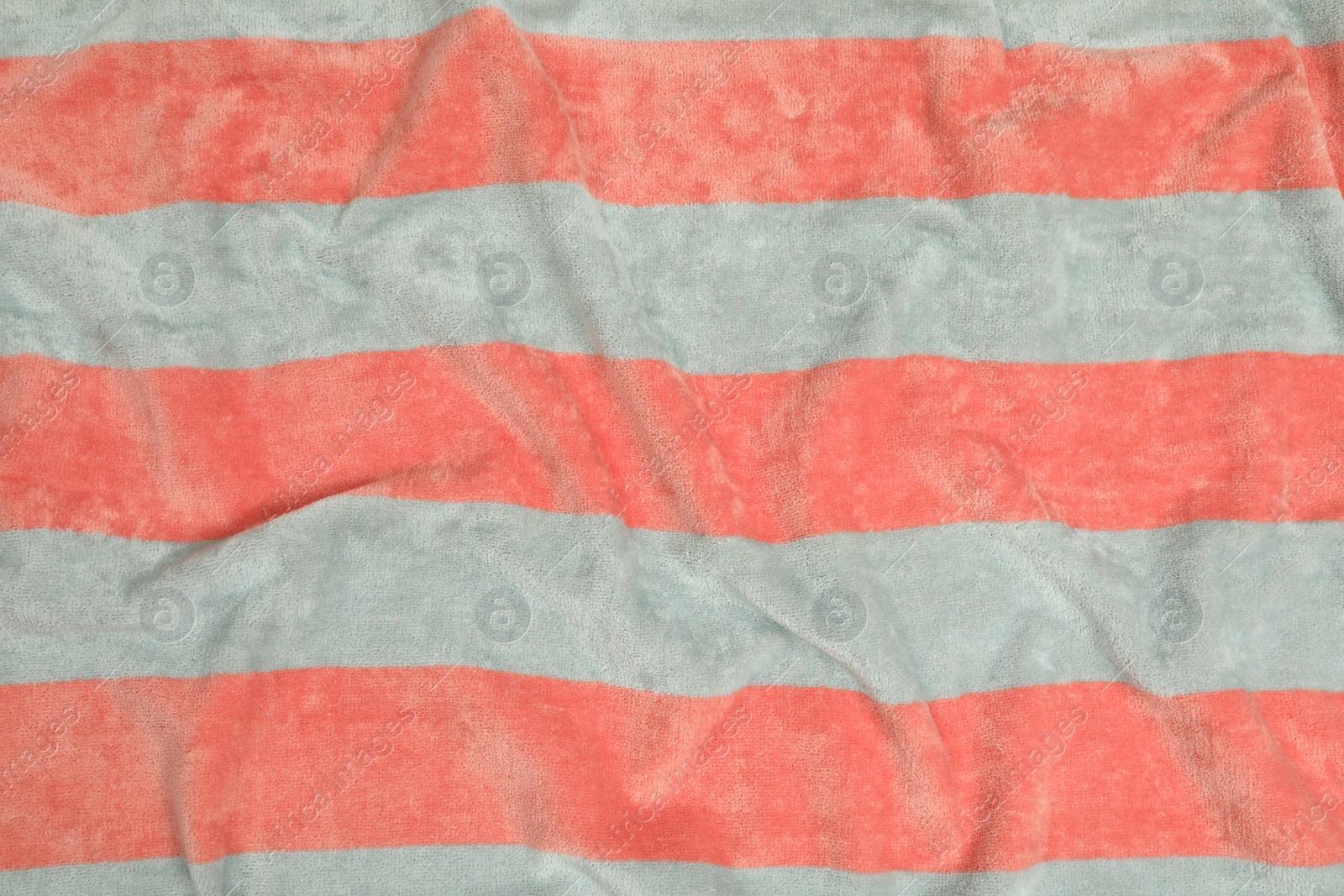 Photo of Crumpled striped beach towel as background, top view