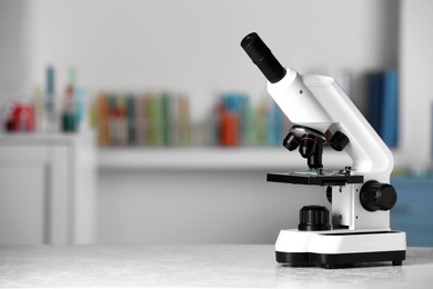 Photo of Modern medical microscope on white table in laboratory, space for text