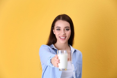 Beautiful young woman drinking milk on color background