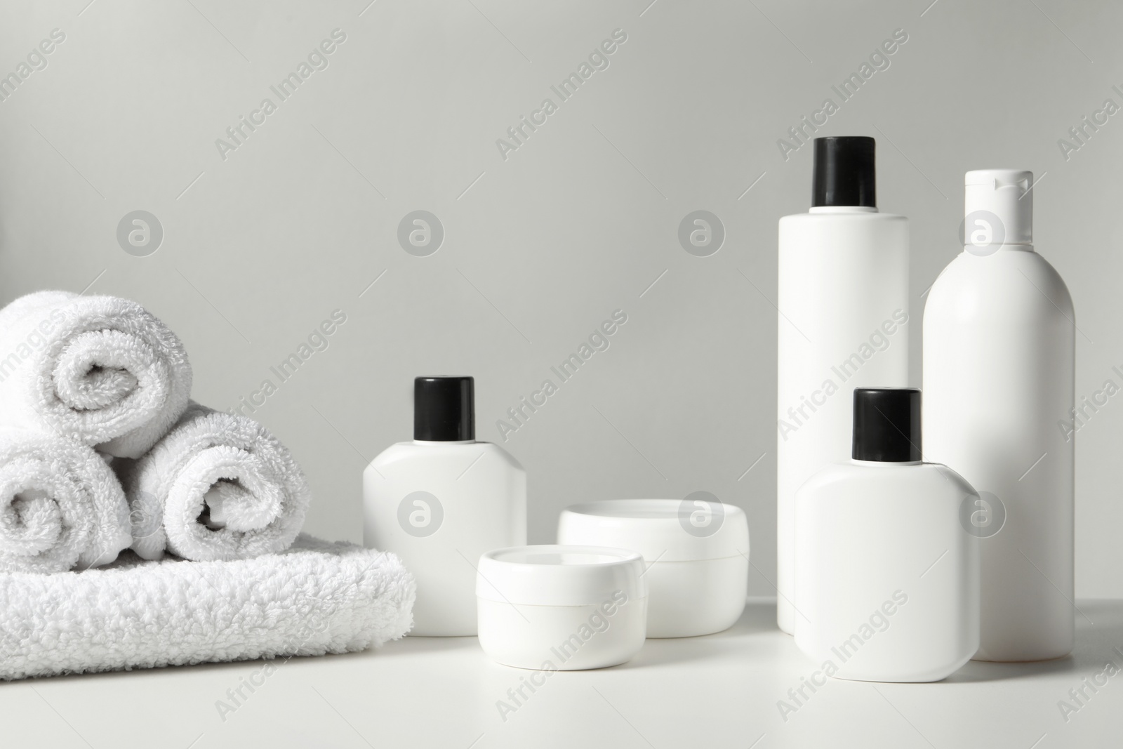 Photo of Different bath accessories and towels on white table against grey background