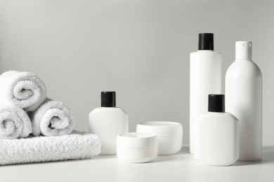 Different bath accessories and towels on white table against grey background