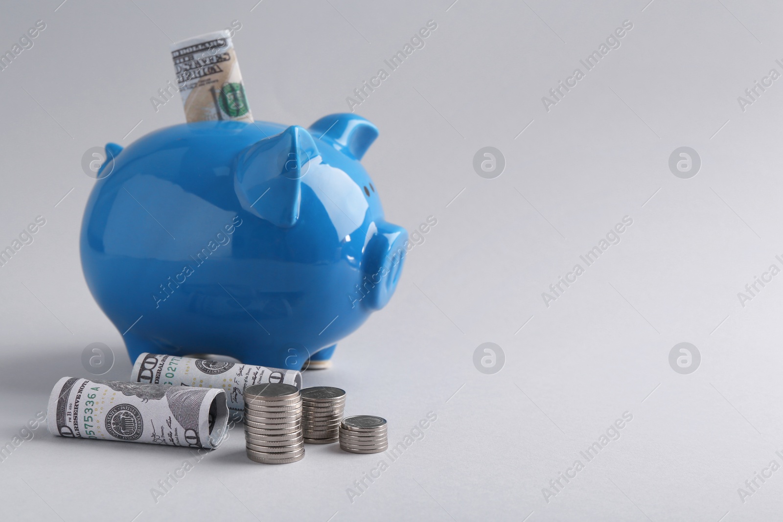 Photo of Financial savings. Piggy bank, dollar banknotes and coins on grey background, space for text