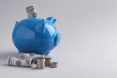 Photo of Financial savings. Piggy bank, dollar banknotes and coins on grey background, space for text