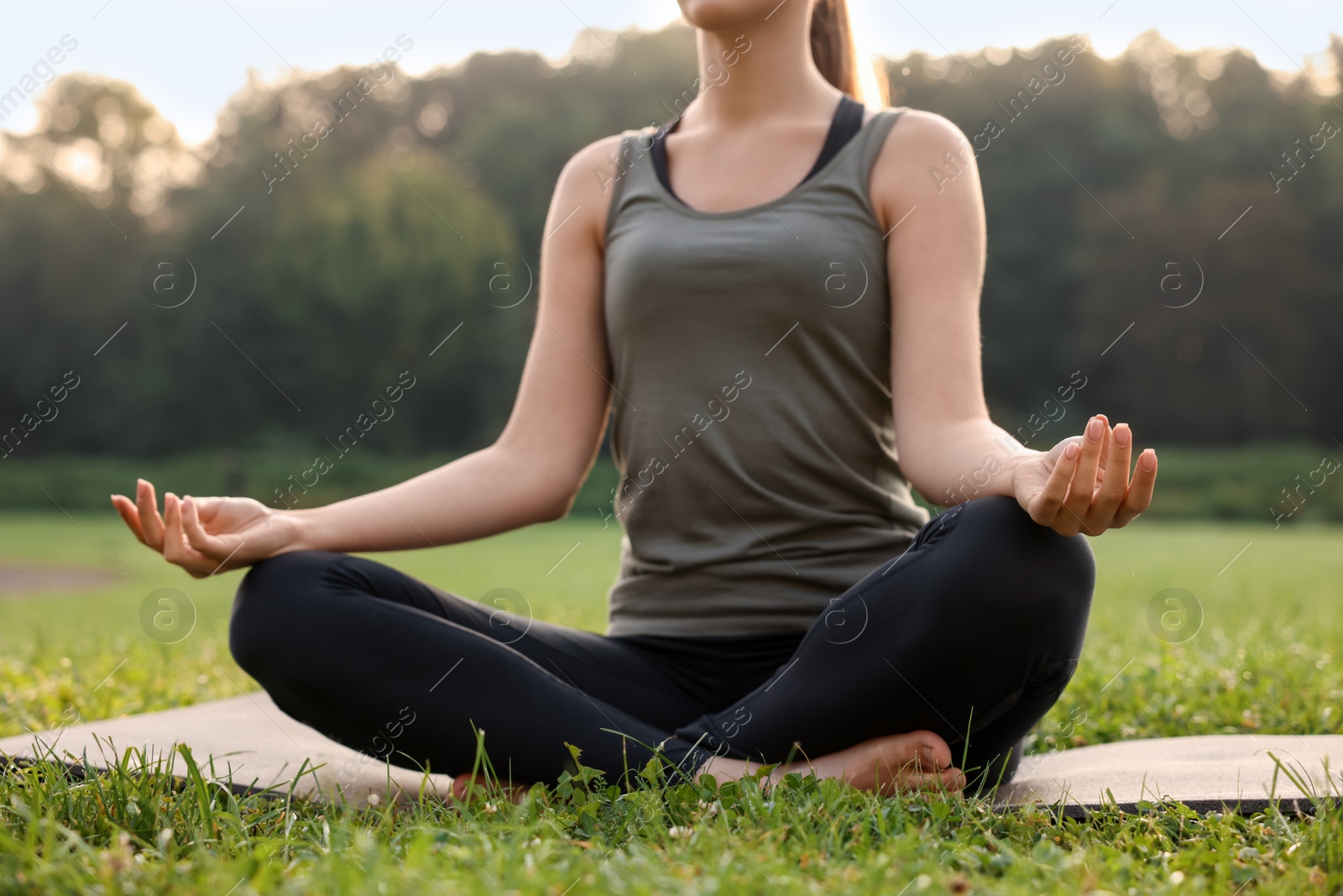 Photo of Woman practicing yoga on mat outdoors, closeup. Lotus pose