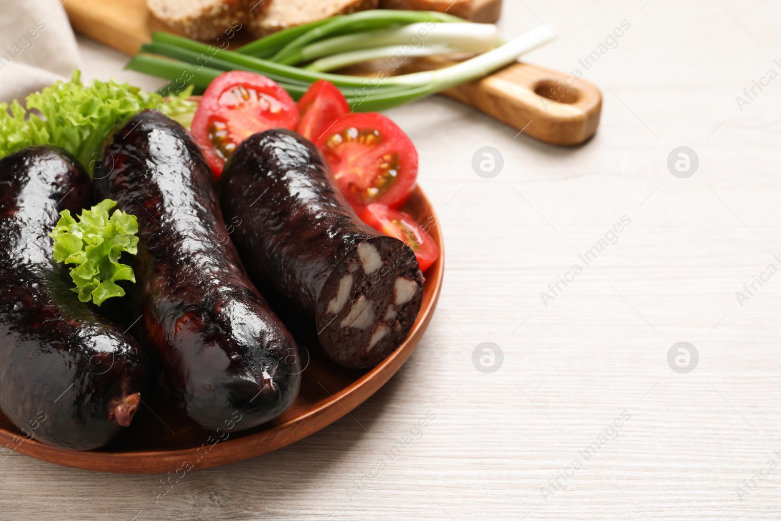 Photo of Tasty blood sausages served on white wooden table, closeup. Space for text