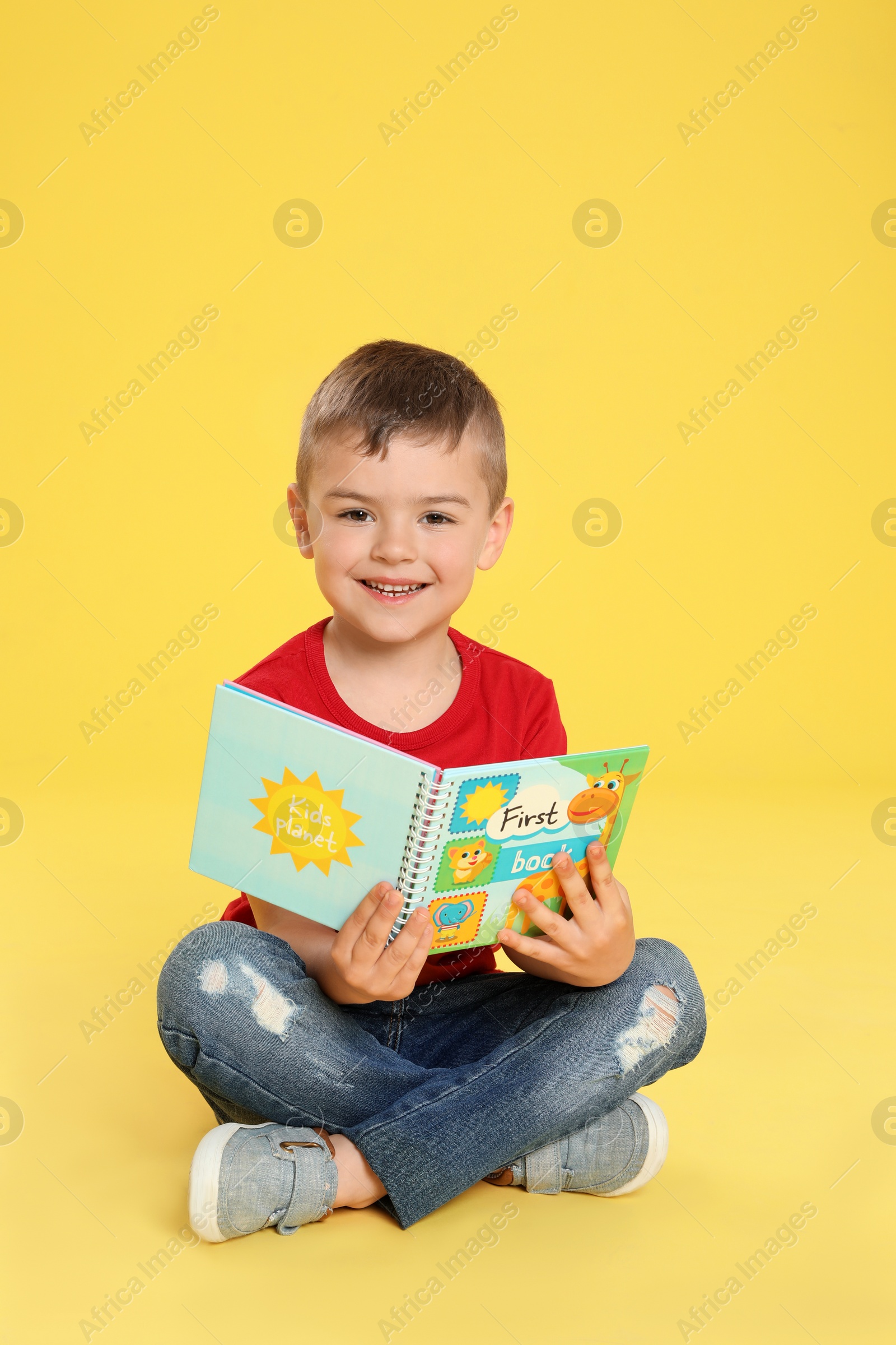 Photo of Cute little boy reading book on color background, space for text