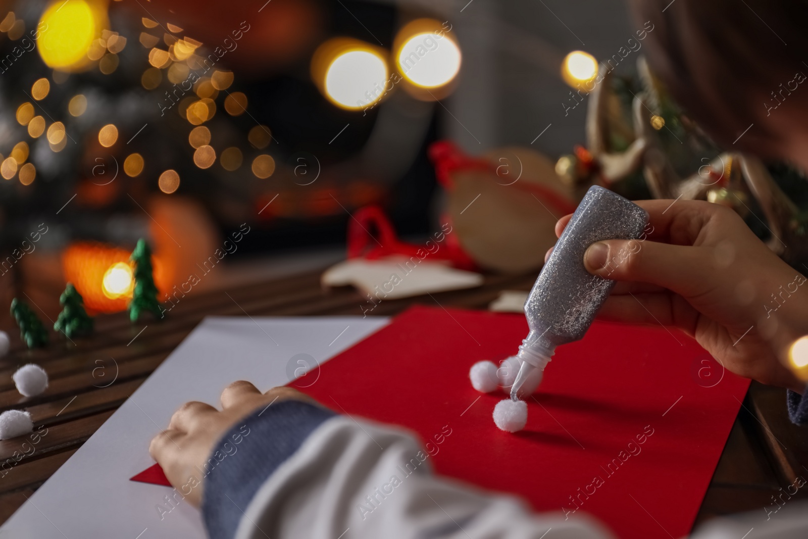 Photo of Little child making Christmas card at wooden table, closeup