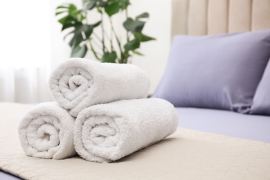Photo of Rolled soft clean towels on bed indoors
