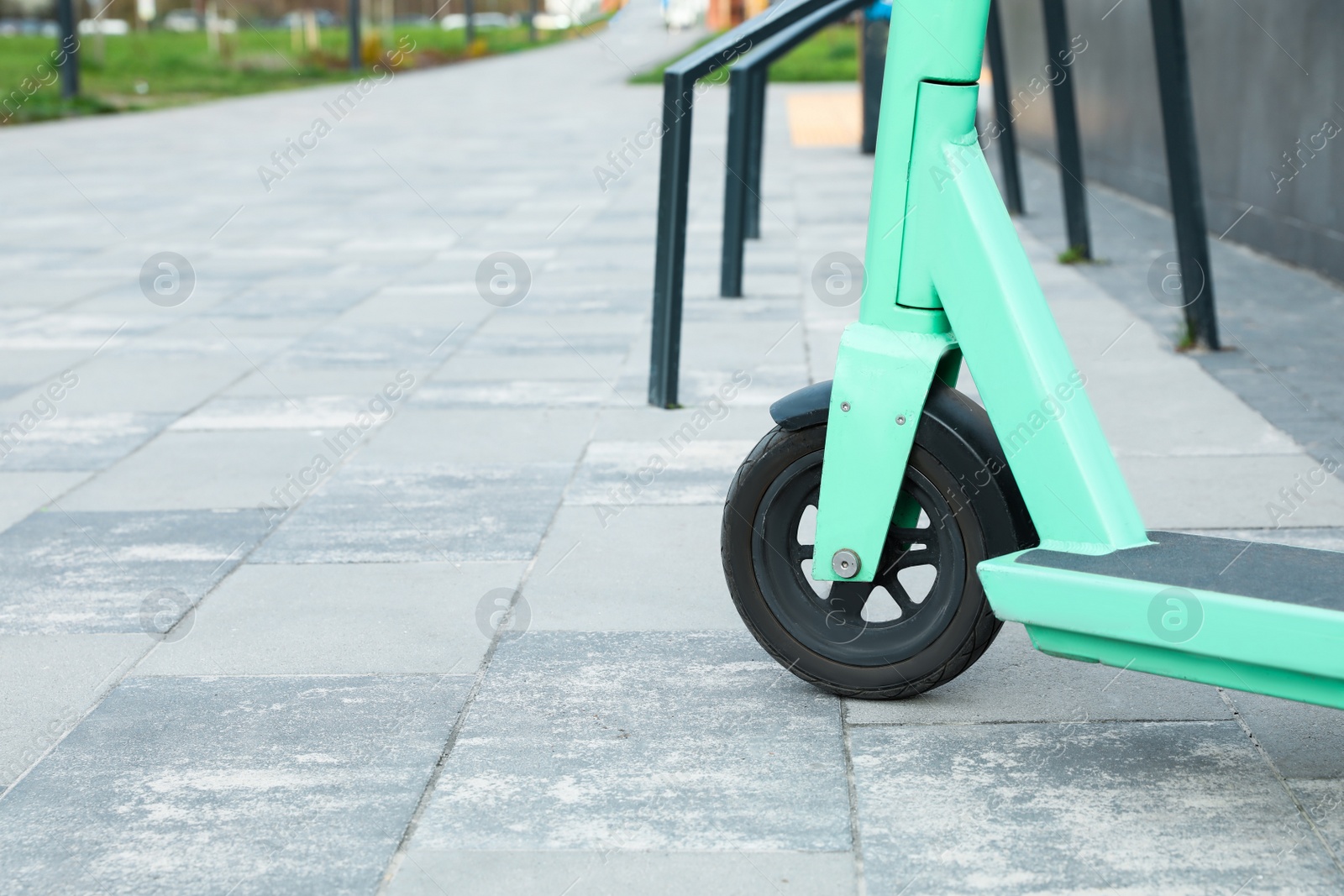 Photo of Closeup view of turquoise kick scooter on pavement. Space for text