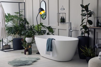 Photo of Stylish bathroom interior with modern tub and beautiful houseplants. Home design