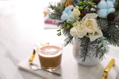 Photo of Beautiful winter wedding bouquet and cup of coffee on white marble table tray, closeup