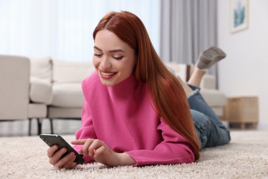 Photo of Happy woman sending message via smartphone on floor at home
