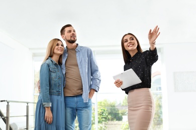 Female real estate agent showing new house to couple, indoors