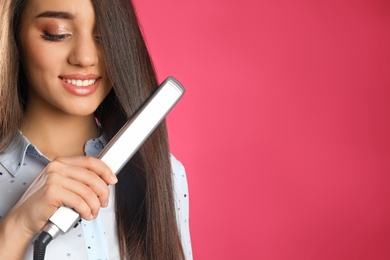 Happy woman using hair iron on color background. Space for text