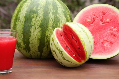 Delicious ripe watermelons and glass of fresh juice on wooden table outdoors