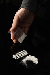 Photo of Drug addiction. Man with cocaine at black table, closeup