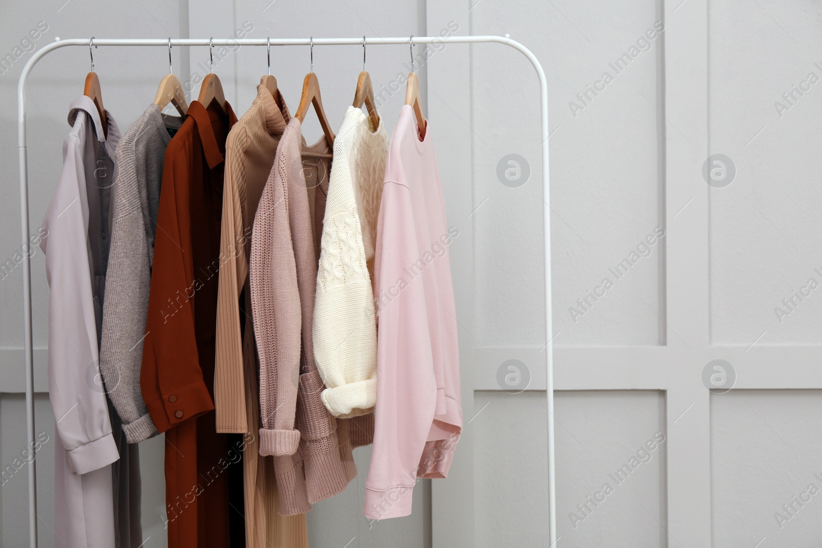 Photo of Rack with different stylish clothes near grey wall. Space for text