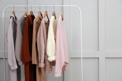 Rack with different stylish clothes near grey wall. Space for text