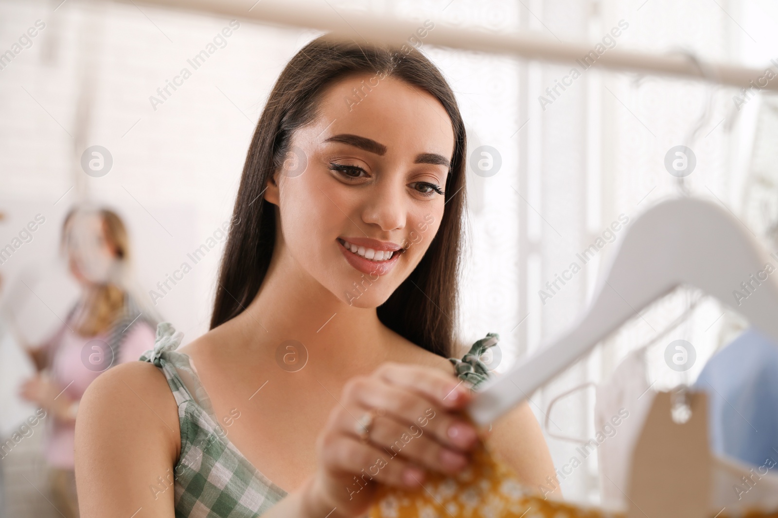 Photo of Woman choosing dress to buy in showroom